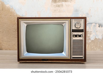 Retro old tv with blank screen on wooden table with old concrete wall background, front view