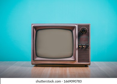 Retro old tv on wooden table with blue concrete wall background.