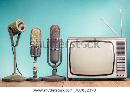Retro old TV receiver and press conference microphones on table front gradient mint green wall background. Broadcasting concept. Vintage instagram style filtered photo