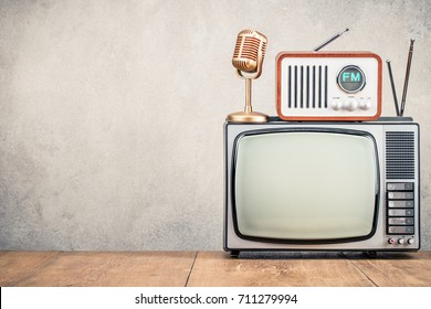 Retro Old TV Set, FM Radio Receiver And Golden Microphone Front Concrete Wall Background. Broadcasting Concept. Vintage Instagram Style Filtered Photo