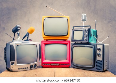 Retro old TV set receivers and microphones on table front textured concrete wall background. Broadcasting concept. Vintage style filtered photo - Shutterstock ID 669147430