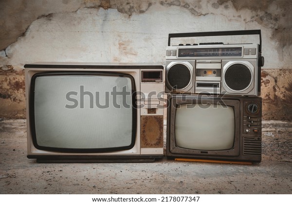 Retro old TVs set and old\
radio cassette front concrete wall background. Vintage style\
filtered photo