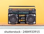 Retro outdated portable stereo boombox radio cassette recorder from 80s front yellow background. Vintage old style filtered photo