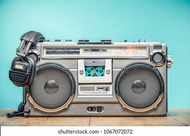 Retro outdated portable stereo boombox radio cassette recorder from circa late 70s with aged headphones front aquamarine wall background. Listening music concept. Vintage old style filtered photo