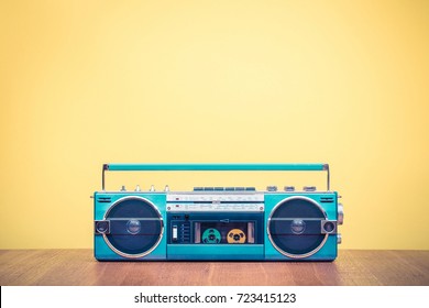 Retro outdated portable stereo mint green radio cassette recorder from 80s front yellow background. Vintage old style filtered photo
