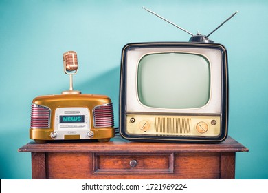 Retro outdated TV set from 60s, old FM radio, golden microphone on oak wooden table front mint blue background. News, press conference or nostalgic music concept. Vintage style filtered photo