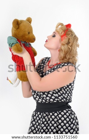 retro photo in 60's style, woman blonde in polka-dot dress with teddy bear in hands