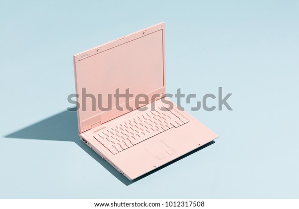 Retro pink laptop on a pastel blue\
background. Technology. Creativity and\
minimalism.