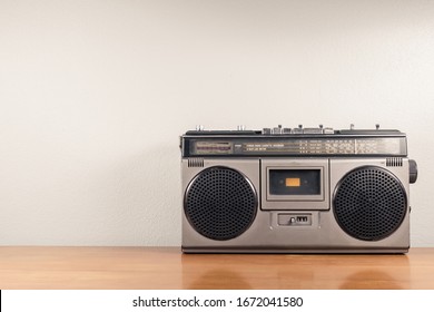 Retro portable radio on the table and concrete wall as space for text, outdated stereo boombox with cassette player