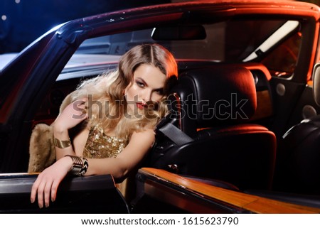 Retro portrait of a beautiful luxury Gatsby woman in black cabriolet car. Vogue fashion style and smoke. Hollywood look. Copy Space