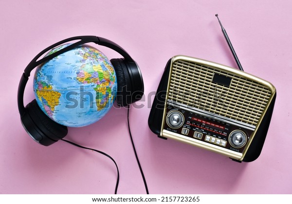 Retro\
radio, headphones and globe on pink background. World radio day.\
world music day. Top view, flat lay, top\
view