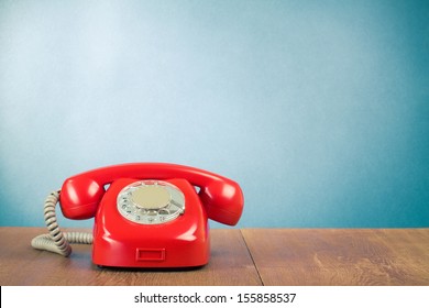Retro red telephone on wood table near aquamarine wall background
