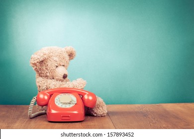 Retro red telephone and Teddy Bear near mint green wall background
