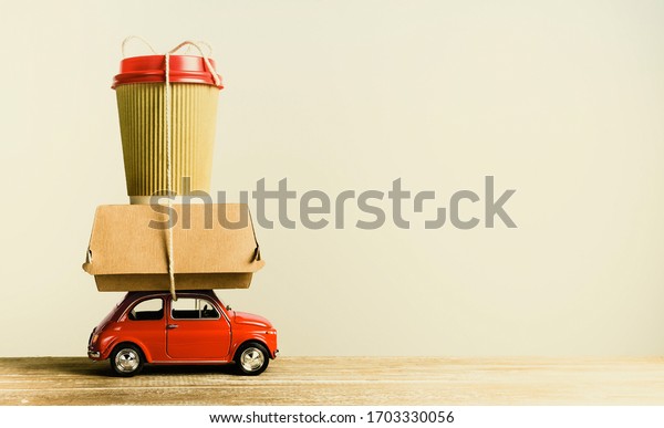 Retro red toy car delivering food order on\
wooden table. Retro toning. Copy\
space