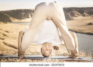 Retro Revival Image Of Funny Man Doing Exercise Of Yoga Outdoor Above River Valley, Dressed In Casual Wear. He Stretching And Standing Like Inverted Pose.