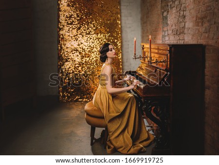 retro romantic elegant woman in golden dress play the piano. backdrop old vintage room brick wall and shine sparkle. Musician with collected bun hairstyle. vogue fashion old style 1920. Carnival party
