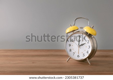 Retro silver alarm clock. 2:00.  am,  pm. Neutral background. Brown wood surface. Horizontal  photography with empty space for text or image.
