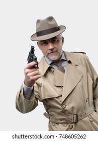 Retro Spy Agent Pointing A Gun, He Is Wearing A Trench Coat And A Hat