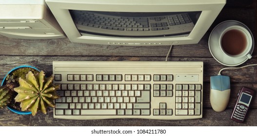 Retro Stationary Computer On A Rustic Wooden Desk, Vintage Workspace. Monitor, Keyboard, Computer Mouse, Top View, Flat Lay
