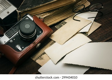 retro still camera and some old photos on wooden table background - Shutterstock ID 299434010