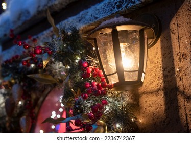Retro street lantern, lamp with yellow glowing light on building wall with snow, winter decoration in cold weather. High quality photo