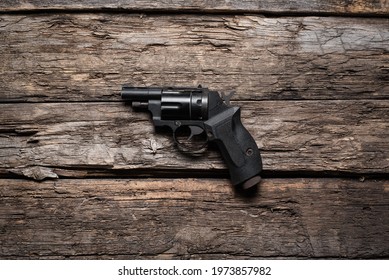 Retro Style Airsoft Handgun On The Old Wooden Table Background.