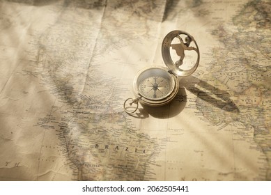 Retro style antique golden compass (sundial) and old nautical chart close-up. Vintage still life. Sailing accessories. Wanderlust, travel and navigation theme. Graphic resources, copy space