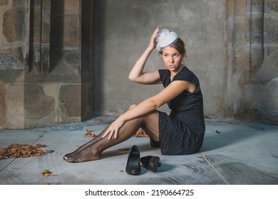 Retro Style Girl With Her Shoes Off Sits On The Stone Floor.