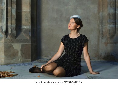 Retro Style Girl With Her Shoes Off Sits On The Stone Floor.