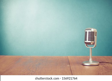 Retro style microphone on table in front aquamarine wall background
