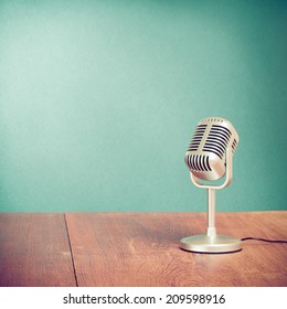 Retro style microphone on table front aquamarine wall background