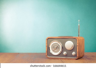 Retro style radio receiver on table in front mint green background