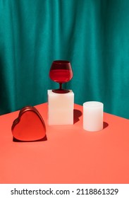 Retro style scene with red wine glass, gift box and product display on bright red table. Silk green curtain background. Minimal vintage style. Valentines day party concept.