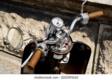 Retro Style Scooter Handle Bar With Rubber Handle And Shiny Chrome Speedometer Instrument. Soft Blurred Stone Wall Background. Circular Mirror. Reansportation Concept. Closeup Detail. Ignition Switch