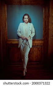 Retro Style. Stunning Young Woman In Elegant White Pantsuit Stands In A Luxurious Vintage Interior. Beauty, Fashion.