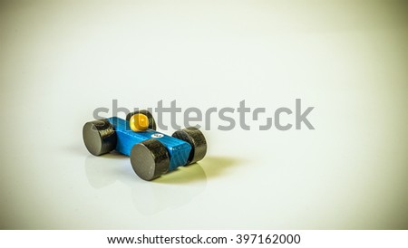 Retro styled or retro color wooden toy race car on empty background. Concept of dream car ownership and financing. Slightly de-focused and close-up shot. Copy space.