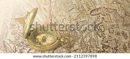 Retro styled golden antique compass (sundial) and old white nautical chart close-up. Vintage still life. Sailing accessories. Travel, navigation concepts, collecting, souvenir, gift, graphic resource