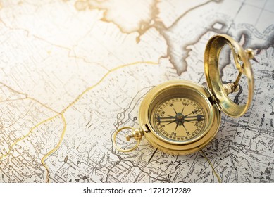 Retro styled golden compass (sundial) and old white nautical chart close-up. Vintage still life. Sailing accessories. Travel and navigation theme