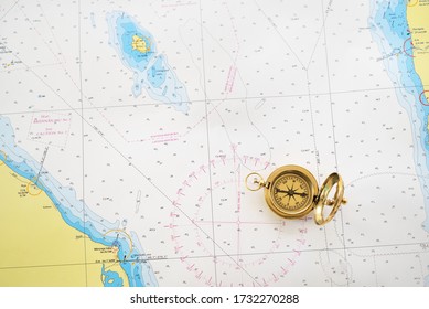 Retro styled golden compass (sundial) and old white nautical chart close-up. Vintage still life. Sailing accessories. Travel and navigation theme