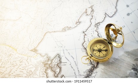 Retro-Styling goldener Kompass (Sundial) und alte weiße nautische Karte, Nahaufnahme. Vintage Stillleben. Segelzubehör. Reisen, Navigation, Geschichte, Sammeln, Hobby. Panoramabild, Kopienraum