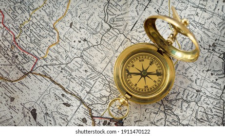 Retro styled golden compass (sundial) and old white nautical chart close-up. Vintage still life. Sailing accessories. Travel, navigation, history, collecting, hobby. Panoramic image, copy space