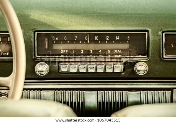 Retro styled image of an old car radio inside a green\
classic car