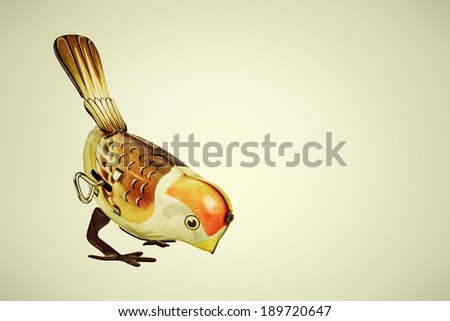 Retro styled image of a tin wind up toy bird on a vintage background