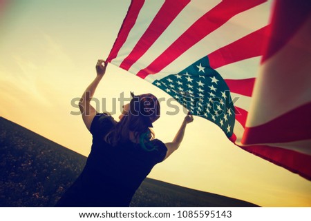 Retro styled photo of young woman in a field with an American Flag.4th July memorial day concept.