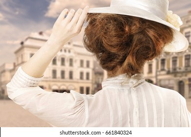 Retro Styled Picture Of Woman In Victorian Hat Looking At The City Street In Europe. Sepia Filter. 