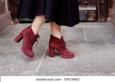 Retro styled portrait. Teacher woman in old fashioned classic outfit wearing burgundy suede boots on heels at the entrance.
