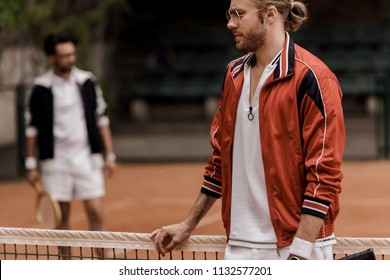 Retro Styled Tennis Player Leaning On Tennis Net During Game At Tennis Court