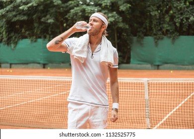 Retro Styled Tired Tennis Player With Towel Drinking Water On Tennis Court