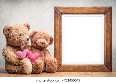 Retro Teddy Bear Toys With Handmade Valentine Love Hearts And Old Oak Wooden Photo Frame On Table Front Concrete Wall Background. Vintage Instagram Old Style Filtered Photo
