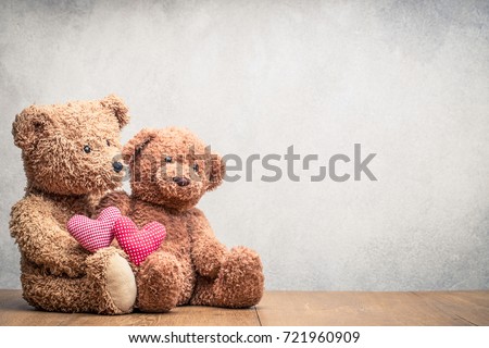 Retro Teddy Bear toys pair with handmade Valentines day love hearts front concrete wall background. Vintage instagram old style filtered photo
